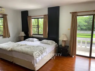 Spacious bedroom with twin beds and balcony view in serene setting.