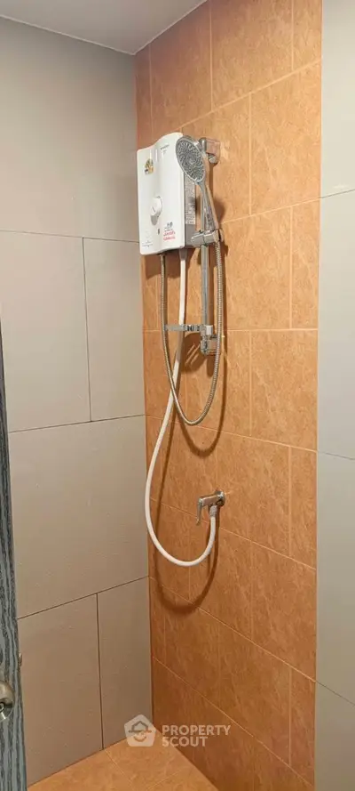 Modern bathroom with tiled walls and electric shower unit, ideal for compact spaces.