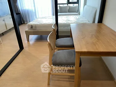 Modern studio apartment with wooden furniture and large windows for natural light.