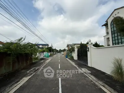 Charming suburban street with elegant houses and lush greenery under a cloudy sky.