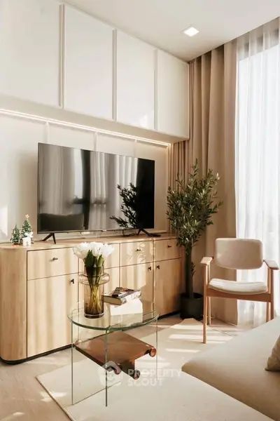 Modern living room with stylish furniture, large TV, and natural light from floor-to-ceiling windows.