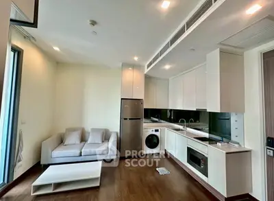 Modern open-layout living room with kitchen, featuring sleek appliances and cozy seating area.