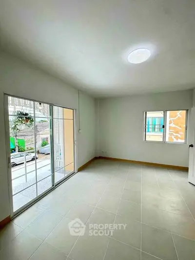 Spacious empty room with large windows and tiled floor, perfect for customization.