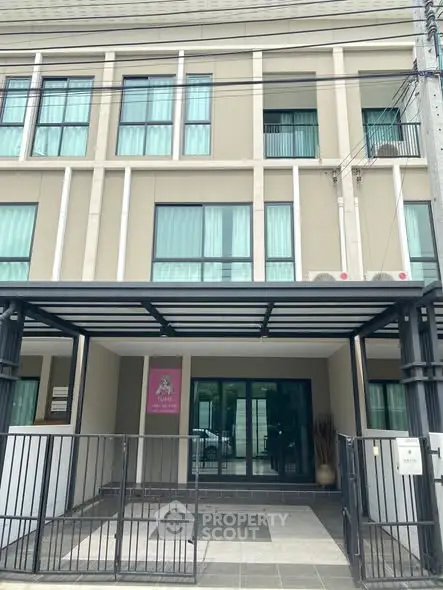 Modern townhouse exterior with gated entrance and large windows.