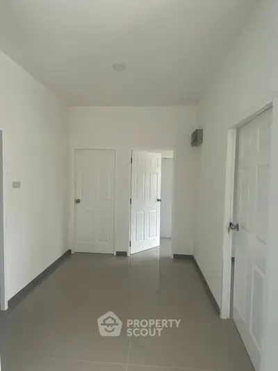 Spacious empty room with white doors and tiled floor, ideal for customization.