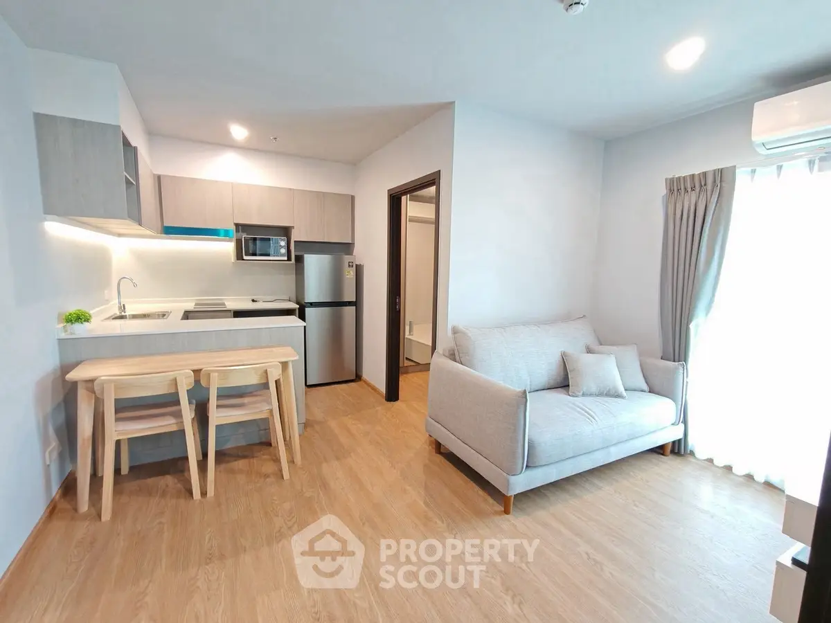 Modern open-plan living room with kitchen, featuring sleek furniture and natural light.