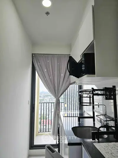 Modern kitchen with balcony view, sleek cabinetry, and open layout