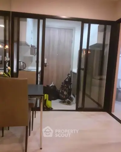 Modern apartment interior with glass partition and compact kitchen area.