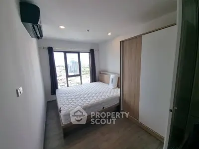Modern bedroom with city view, featuring a comfortable bed and sleek wardrobe in a high-rise apartment.