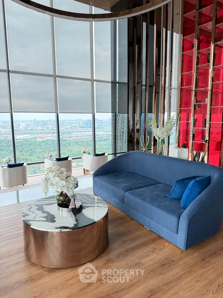 Luxurious living room with panoramic city view, modern blue sofa, and elegant decor in high-rise apartment.