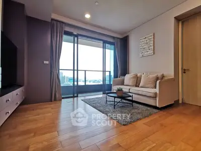 Spacious living room with balcony and city view, featuring modern decor and wooden flooring.