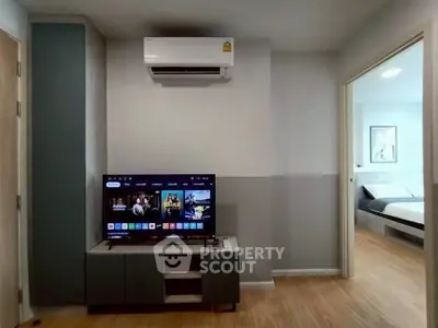 Modern living room with air conditioning and TV, open doorway to bedroom.