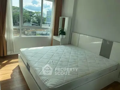 Bright bedroom with large window and modern furniture, perfect for relaxation.