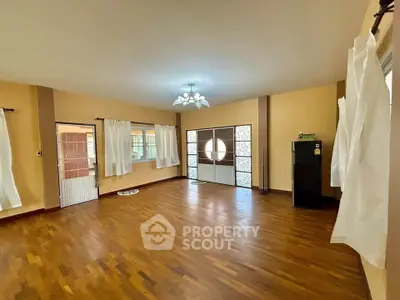 Spacious living room with wooden flooring and large windows for natural light.