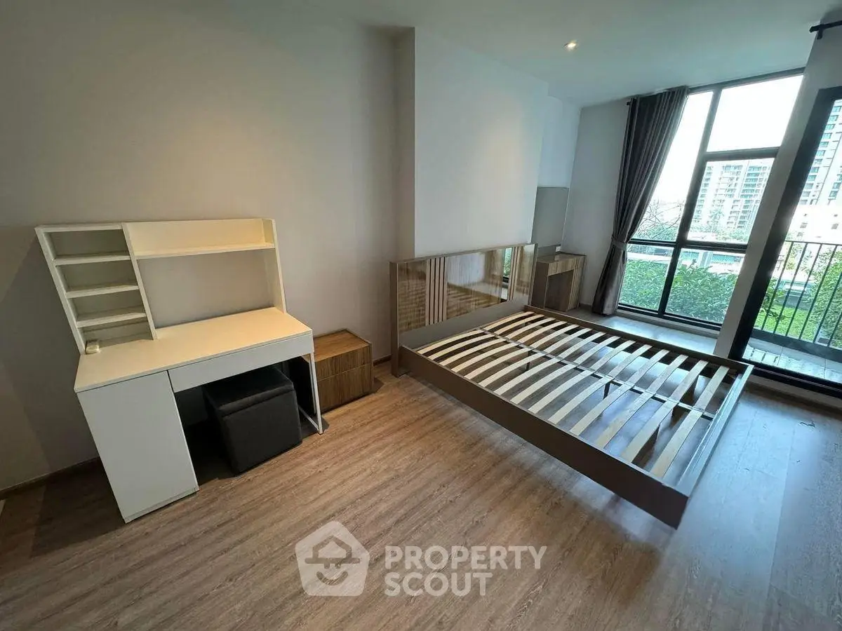 Spacious bedroom with modern furniture and large window offering city view