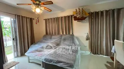 Spacious living room with ceiling fan and large windows overlooking garden