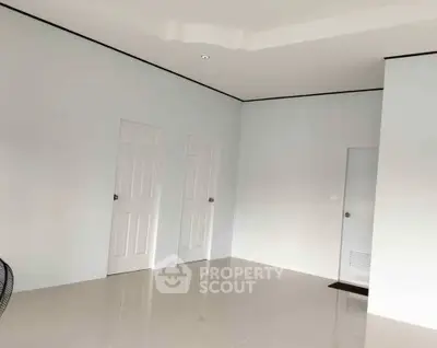 Spacious minimalist interior with sleek white doors and glossy tiled flooring, perfect for modern living.