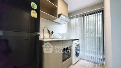 Modern kitchen with washing machine and oven, sleek cabinetry, and natural light.