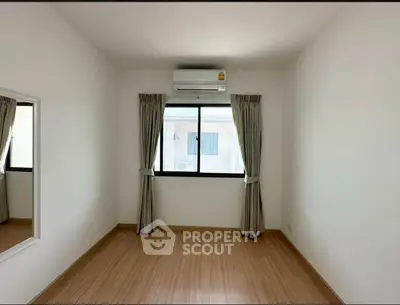 Spacious empty room with wooden flooring and large window, perfect for customization.