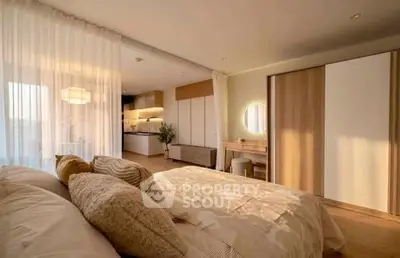 Spacious bedroom with modern decor and open layout leading to a stylish kitchen.