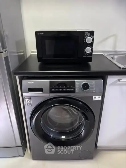 Modern kitchen with washing machine and microwave setup