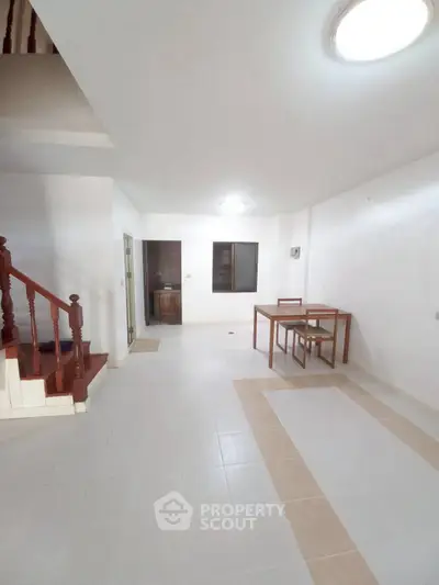Spacious open-plan living area with modern staircase and dining set.
