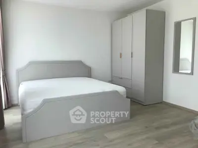 Spacious minimalist bedroom with modern furniture and ample natural light.