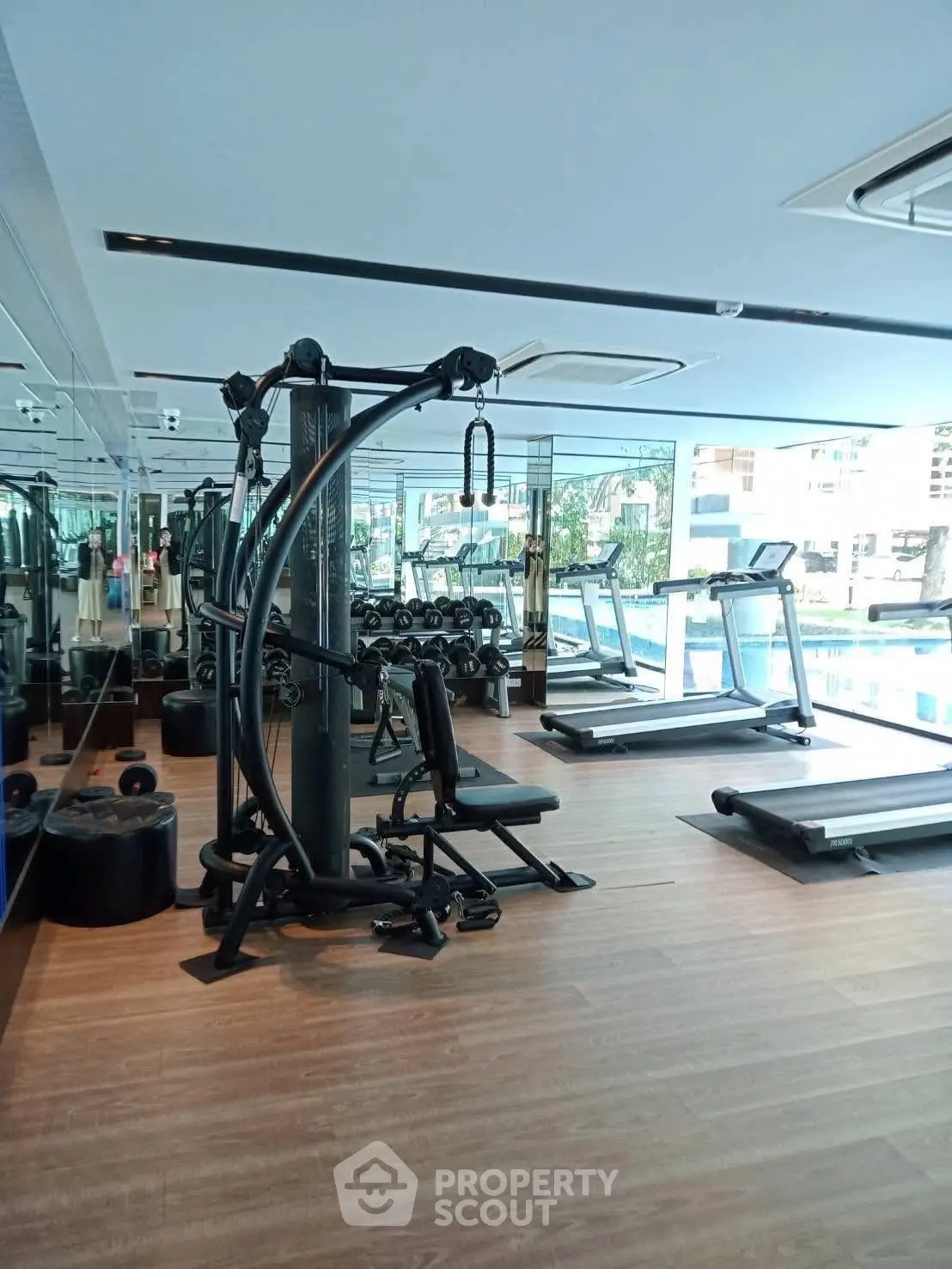 Modern gym with state-of-the-art equipment and large windows offering a bright and inviting workout space.