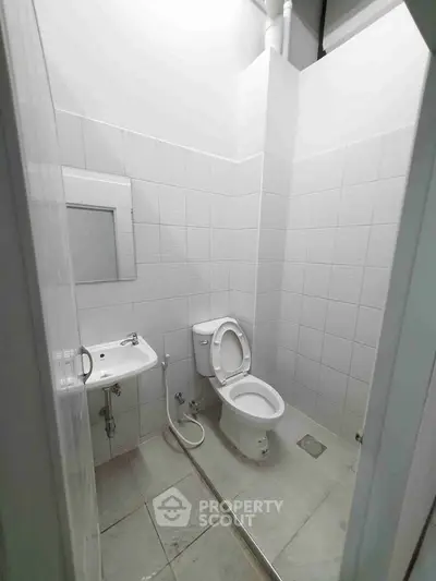 Minimalist bathroom with white tiles and modern fixtures in a real estate property.