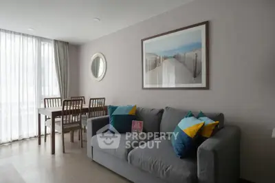 Modern living room with stylish decor and natural light, featuring a cozy sofa and dining area.