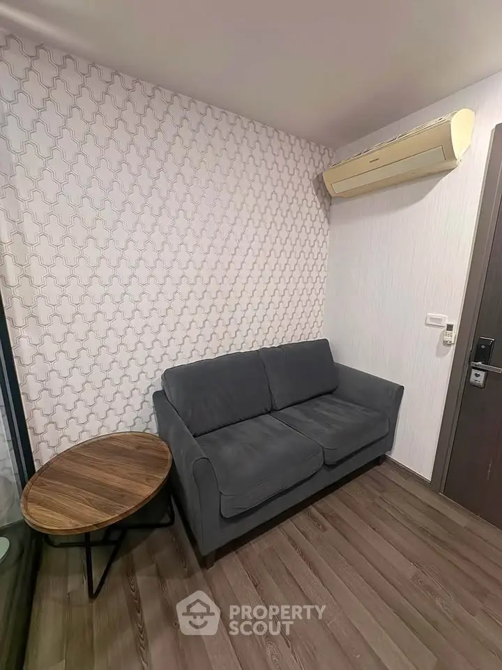 Cozy living room with modern gray sofa and stylish wooden side table, featuring elegant wallpaper and air conditioning.