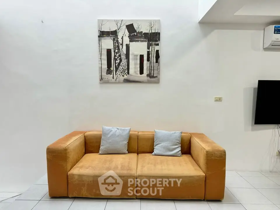Modern living room with stylish orange sofa and contemporary wall art, perfect for cozy relaxation.