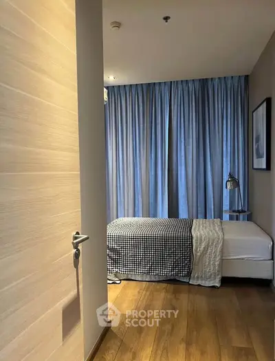 Cozy bedroom with wooden flooring and elegant blue curtains