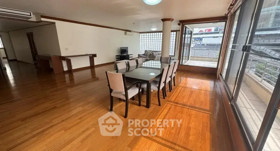 Spacious dining area with large windows and wooden flooring in modern apartment.