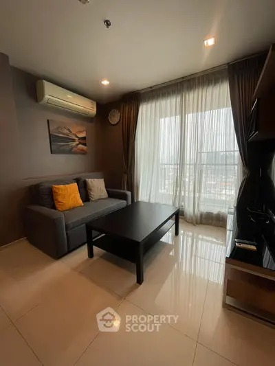 Modern living room with sleek furniture and large window offering natural light.