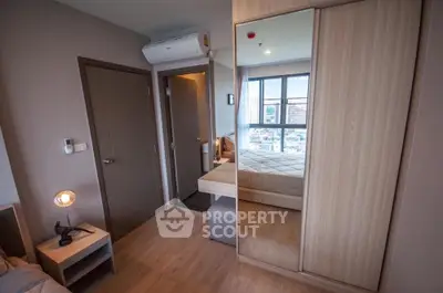 Modern bedroom with wooden flooring and large wardrobe reflecting city view