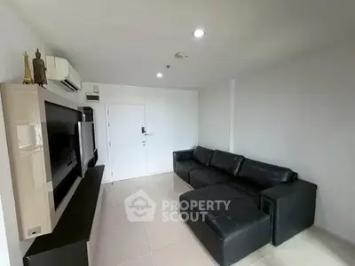 Modern living room with sleek black sofa and wall-mounted TV in minimalist design.
