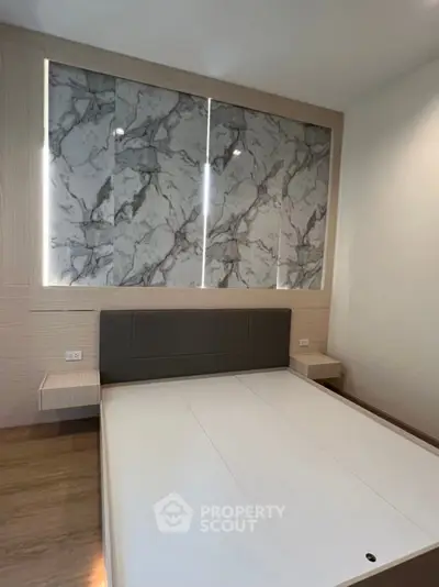 Modern bedroom with stylish marble accent wall and sleek wooden flooring.