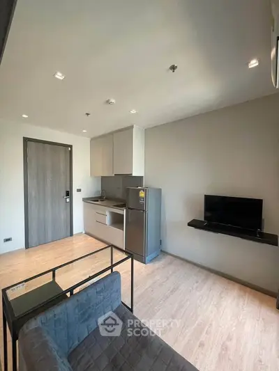 Modern studio apartment with compact kitchen and cozy living area, featuring sleek design and efficient use of space.