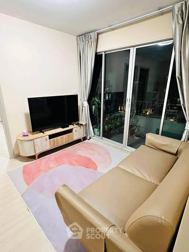 Modern living room with sleek sofa, large TV, and balcony access, perfect for relaxation and entertainment.