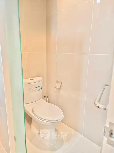 Modern bathroom with sleek white tiles and contemporary toilet design.