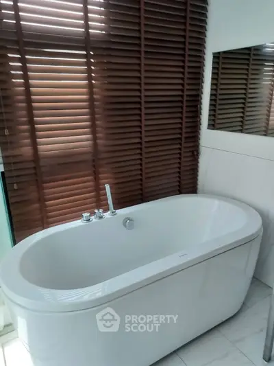 Luxurious bathroom with elegant freestanding bathtub and stylish blinds.