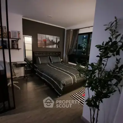Cozy bedroom with modern decor and city view from window.