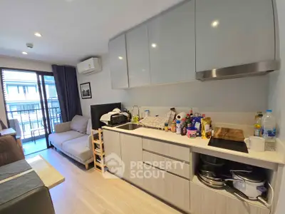 Modern compact living room with open kitchen and balcony view, featuring sleek cabinetry and cozy seating.