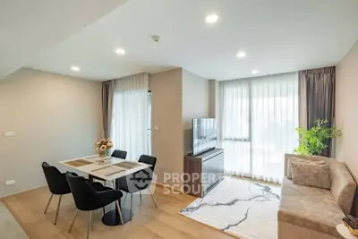 Modern living room with dining area, sleek furniture, and large windows for natural light.