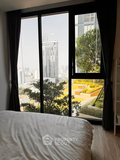 Luxurious bedroom with stunning city view and lush greenery outside the window.