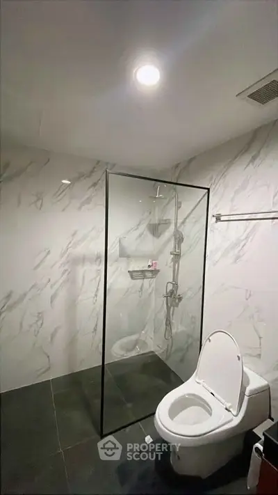 Modern bathroom with marble walls and glass shower enclosure