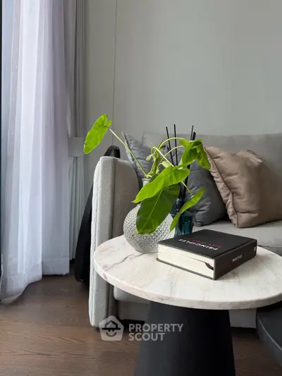 Stylish living room corner with modern sofa, elegant side table, and lush green plant for a cozy ambiance.