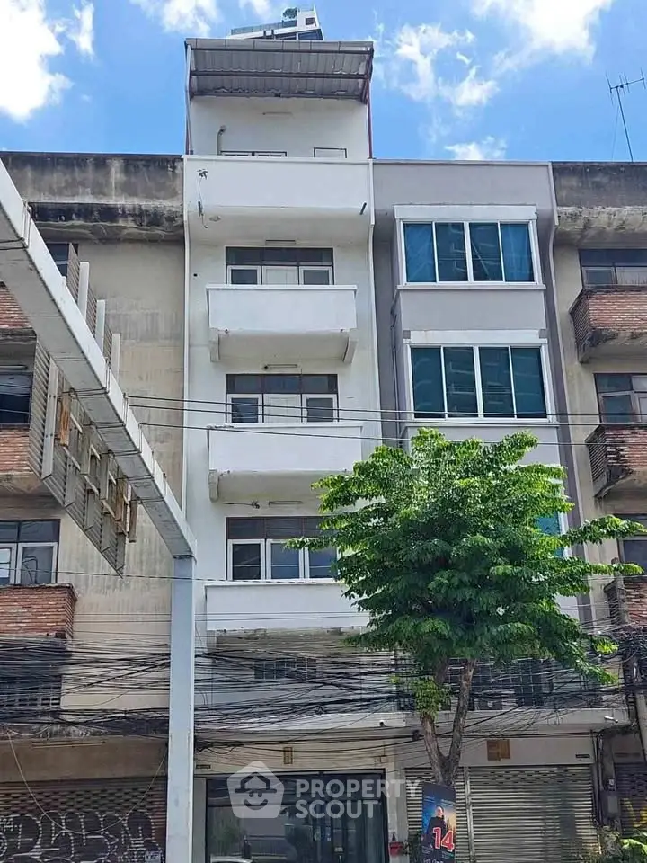 Modern multi-story building with balconies and large windows in urban setting.