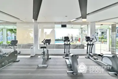 Modern gym with state-of-the-art equipment and pool view in luxury residential complex.